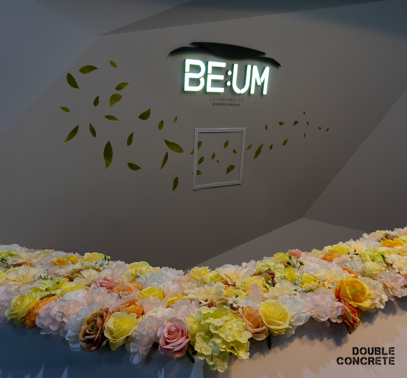 BE:UM 전시 공간, 꽃 장식과 미니멀한 디자인의 입구