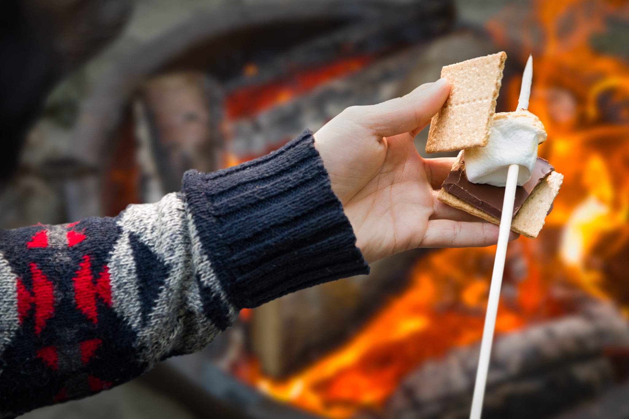 Closeup of hands building smore with roasted marshmallow and chocolate