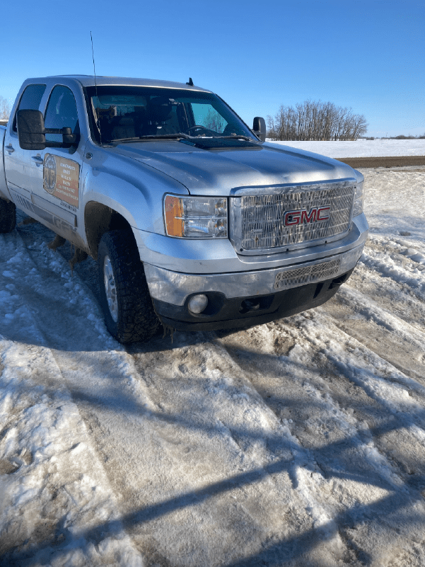 Silver GMC Sierra pickup truck parked on snow for commercial hauling transport.