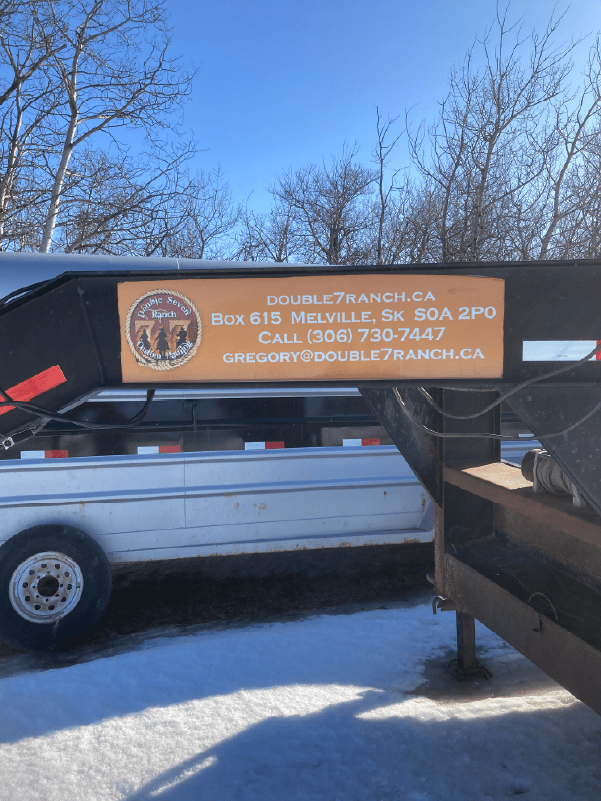 Close-up of an orange Double Seven Custom Hauling sign on a white trailer frame.