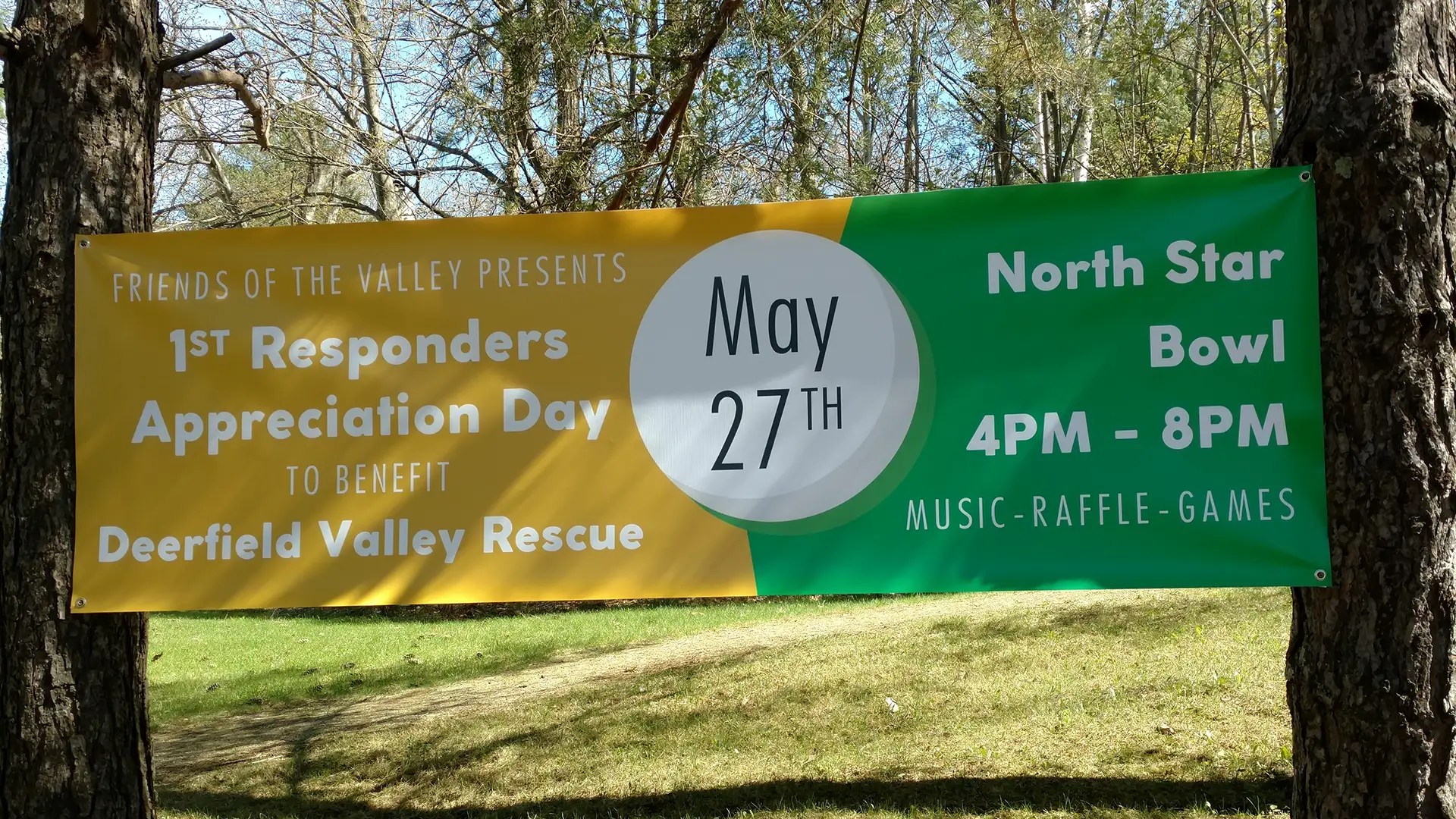 Custom vinyl event banner hung between trees