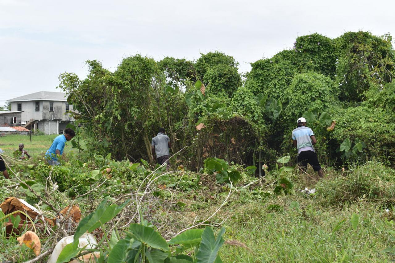 Sophia residents along with members of the Guyana Police Force tackling the overgrowth to clear the designated area where a sports ground will be constructed