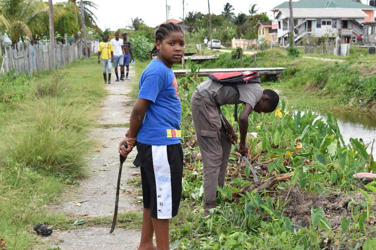 Sophia residents along with members of the Guyana Police Force tackling the overgrowth to clear the designated area where a sports ground will be constructed