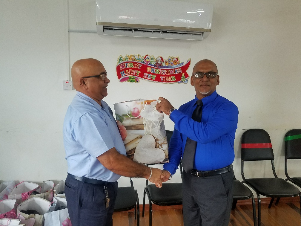 Outgoing REO Denis Jaikaran presents a Christmas hamper to Vice Chairman Sheik Ayube