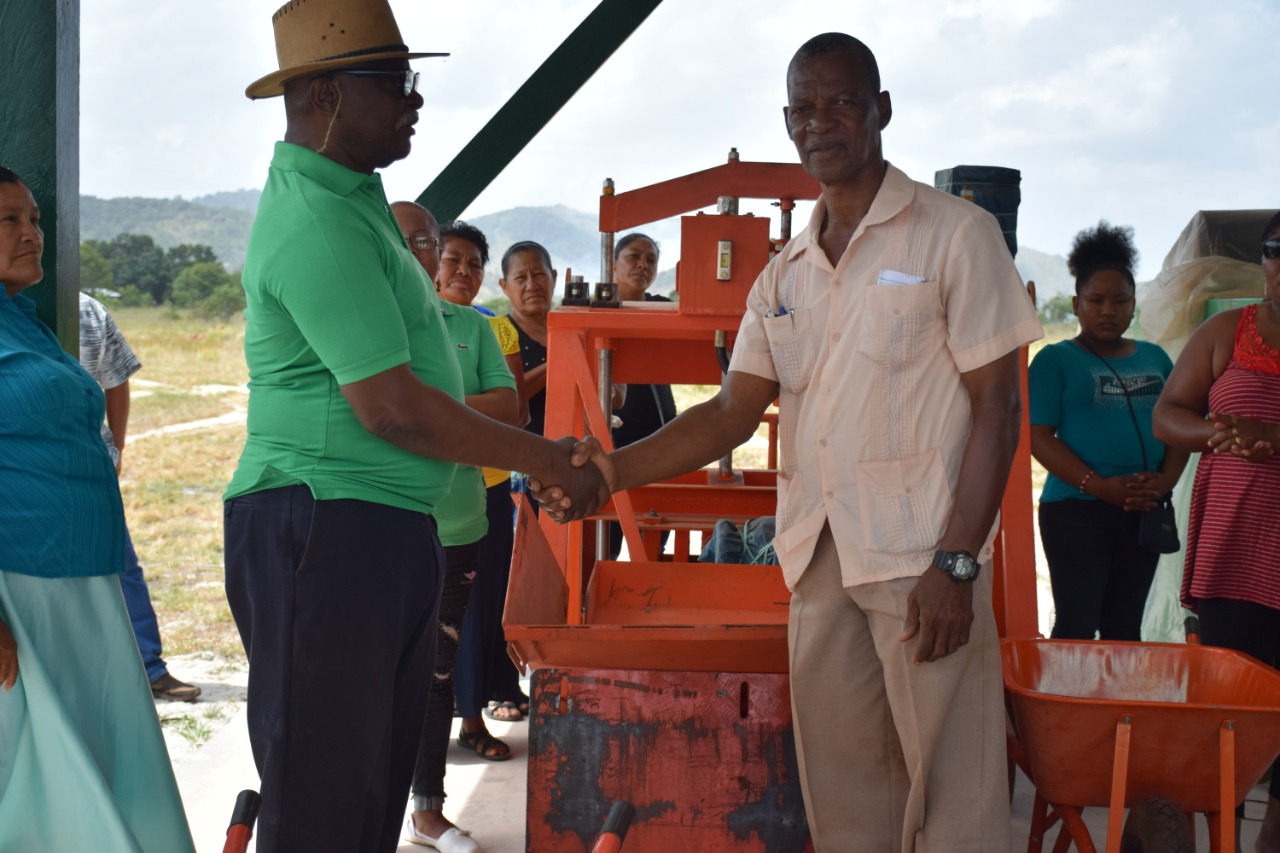 Minister of Citizenship Winston Felix hands over the block making equipment to Aranaputa Neighbourhood Democratic Council Chairman, Virgil Harding