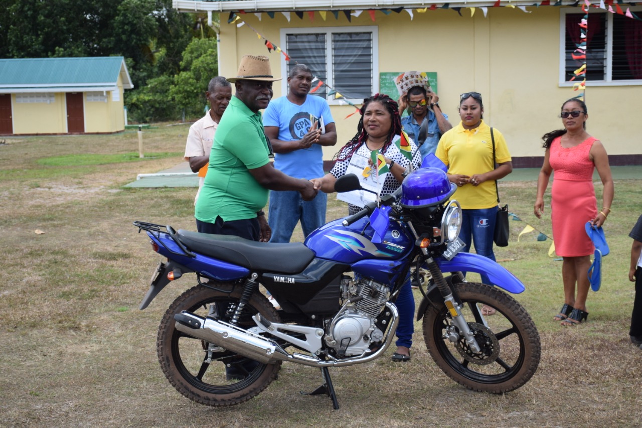 Minister of Citizenship, Winston Felix hands over a motorcycle to Secretary of the Block Making Committee, Mercie Stephna