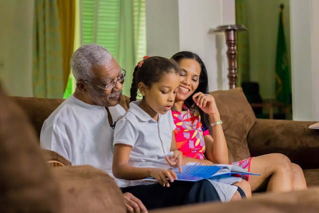 Seven year old Faraa Gaskin reads a book to President David Granger, her grandfather, as her mother, Mrs. Han Granger-Gaskin looks on.
