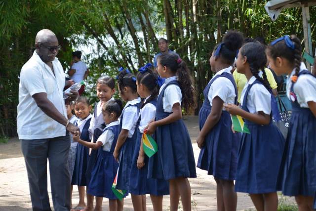 Minister of Citizenship Winston Felix, is greeted by students in Kartabo prior to his hosting a community meeting in village.