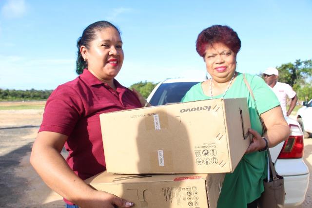 Minister of Social protection, Hon. Amna Ally hands over computer system to Renita Williams for Anthony Williams, a student of the Santa Rosa Secondary School.