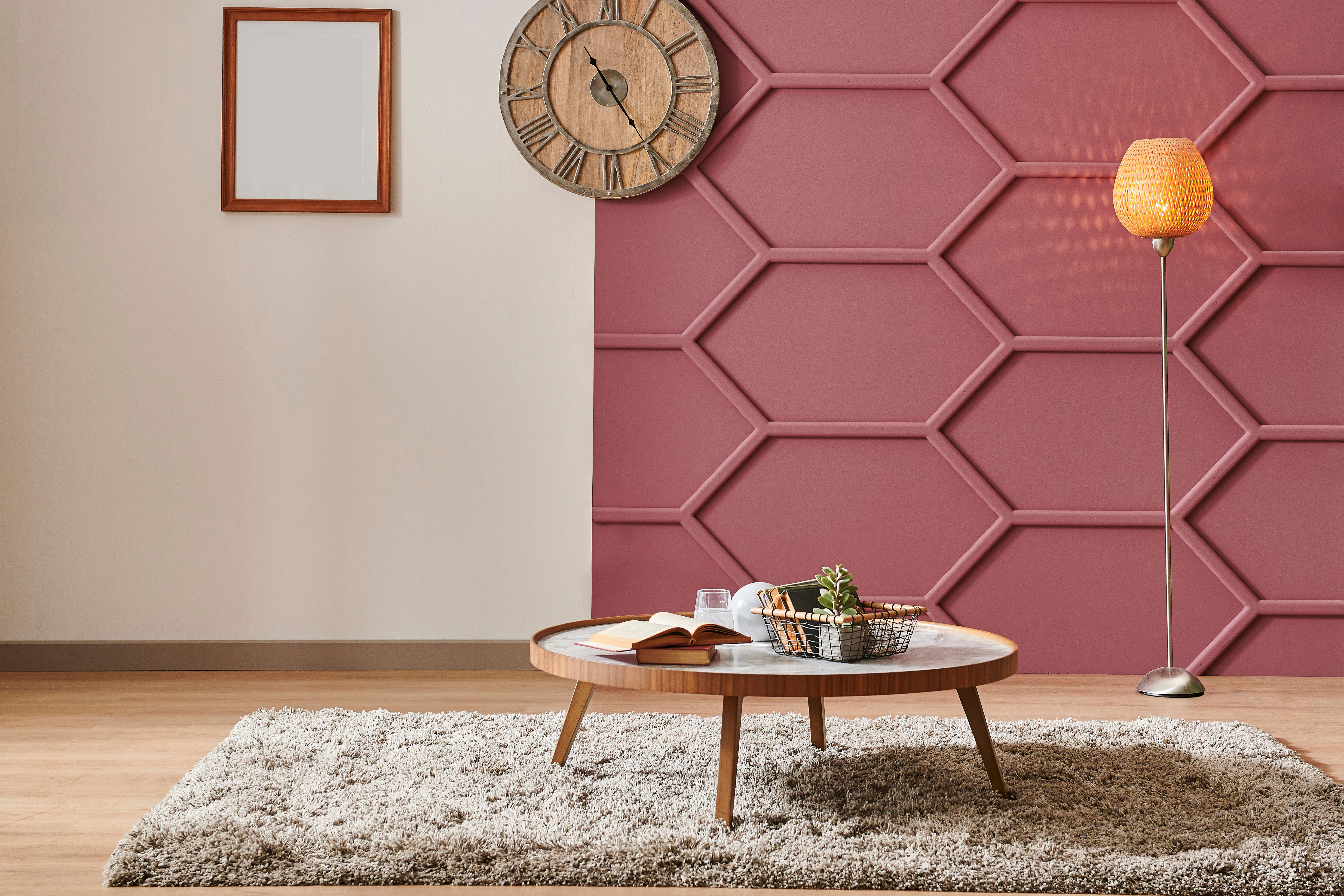 A claret-red textured accent wall wraps a living room corner, echoed by a brass-toned floor lamp beside a round wood table.