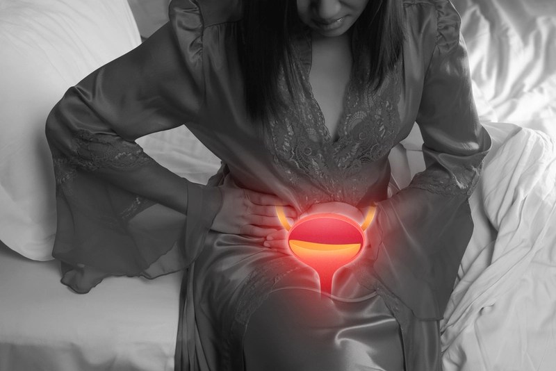 Mulher com dores na região abdominal e figura ilustrativa de bexiga