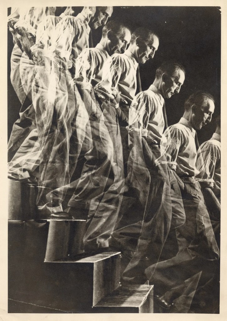 Multiple-exposure photograph of a figure descending a staircase, echoing Marcel Duchamp's own Nude Descending a Staircase by restaging the same layered, sequential movement in real photographic time.