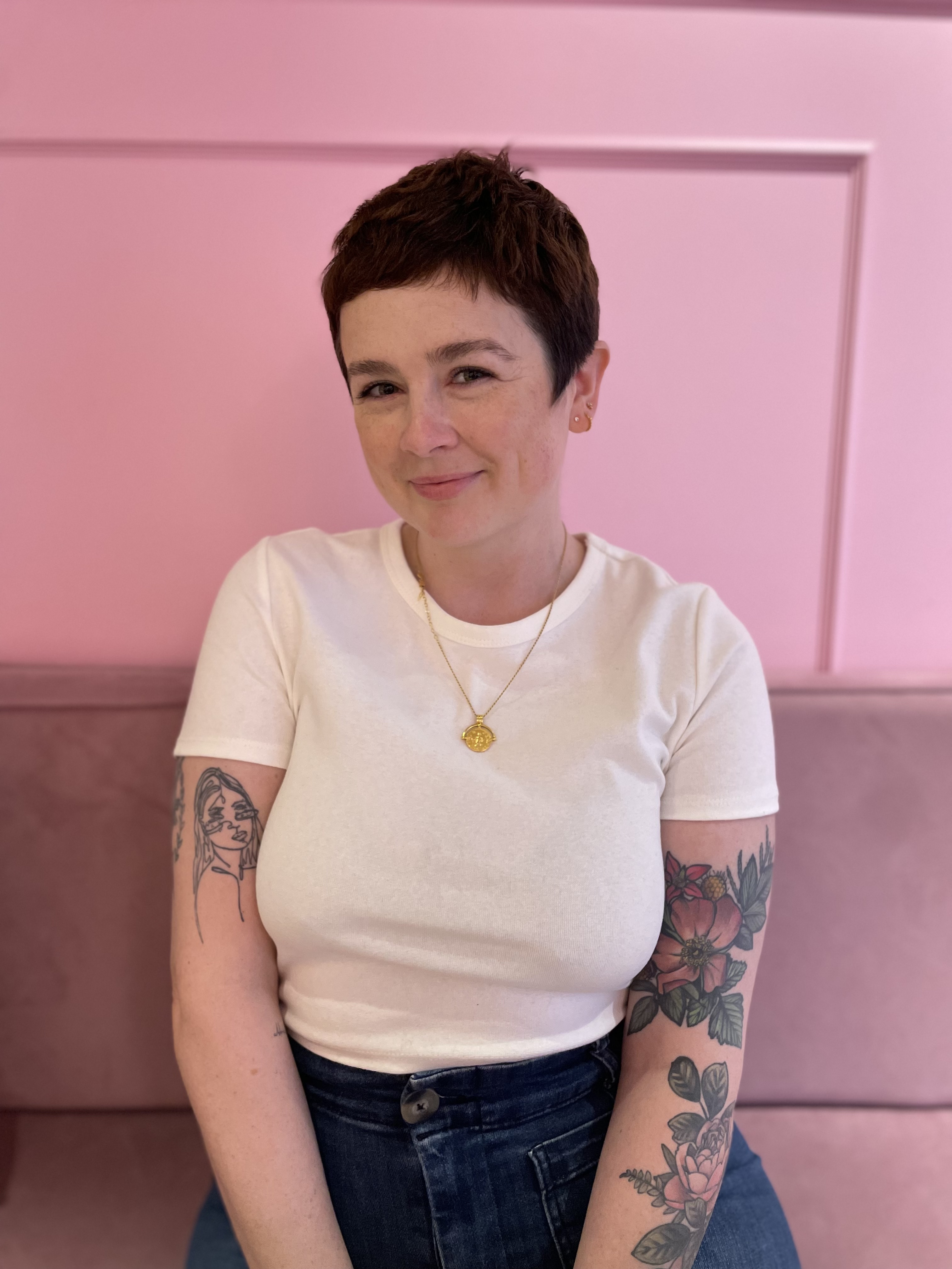 A woman smiling in front of a pink background
