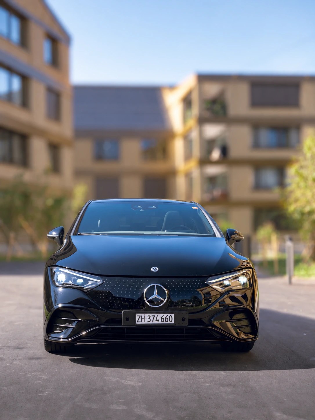 Black Mercedes EQE business sedan with driver, front view