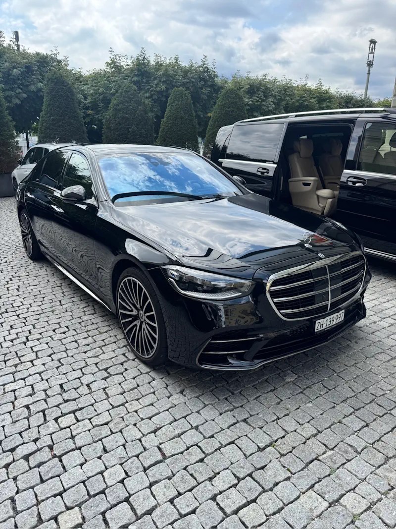 Black Mercedes S-Class with driver, front three-quarter view