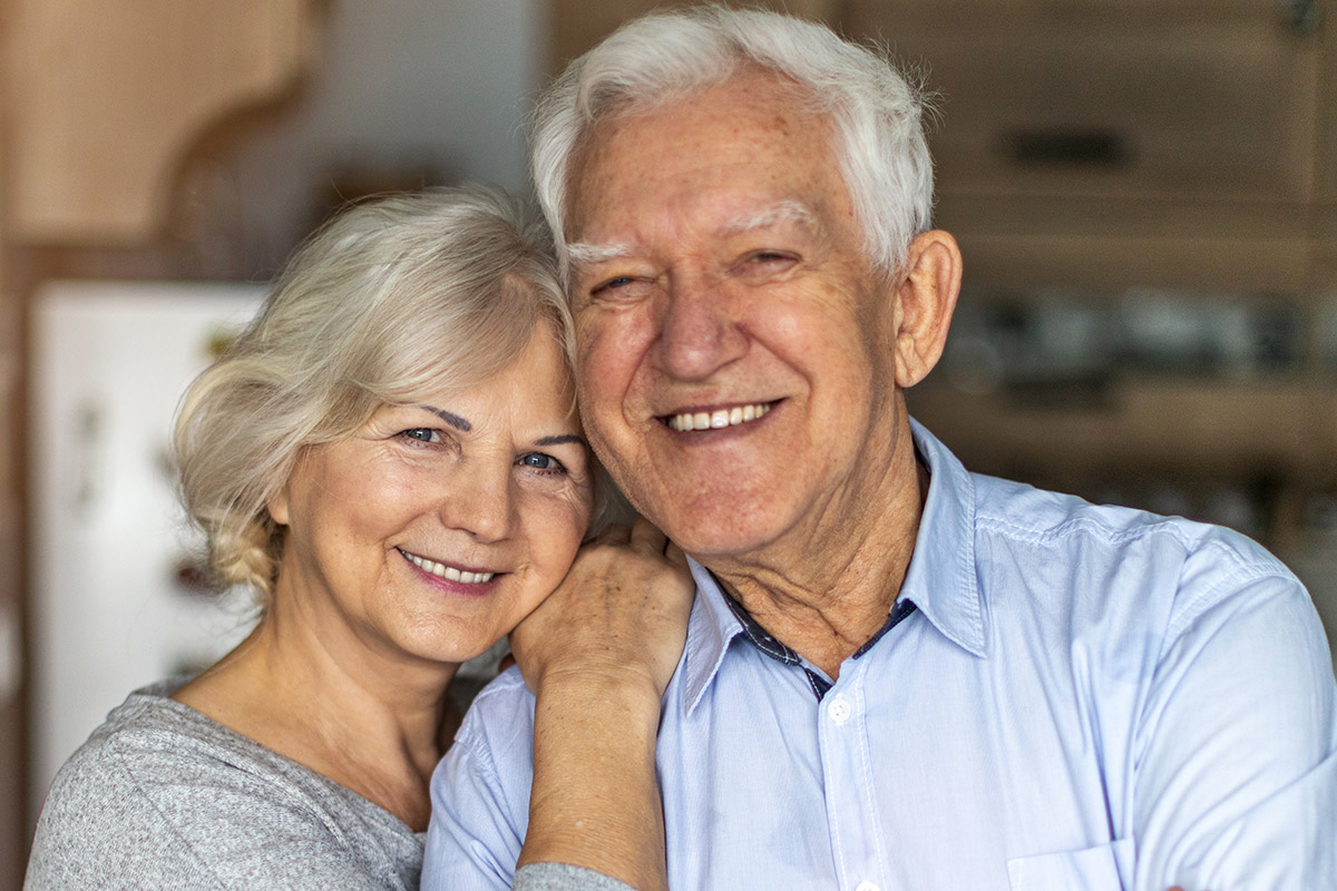 Smiling elderly couple showcasing confidence and happiness after dental implant treatment, reflecting the compassionate care at Palani Center for Dental Implants.