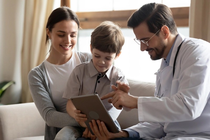 Médico mostrando tablet para filho e mãe