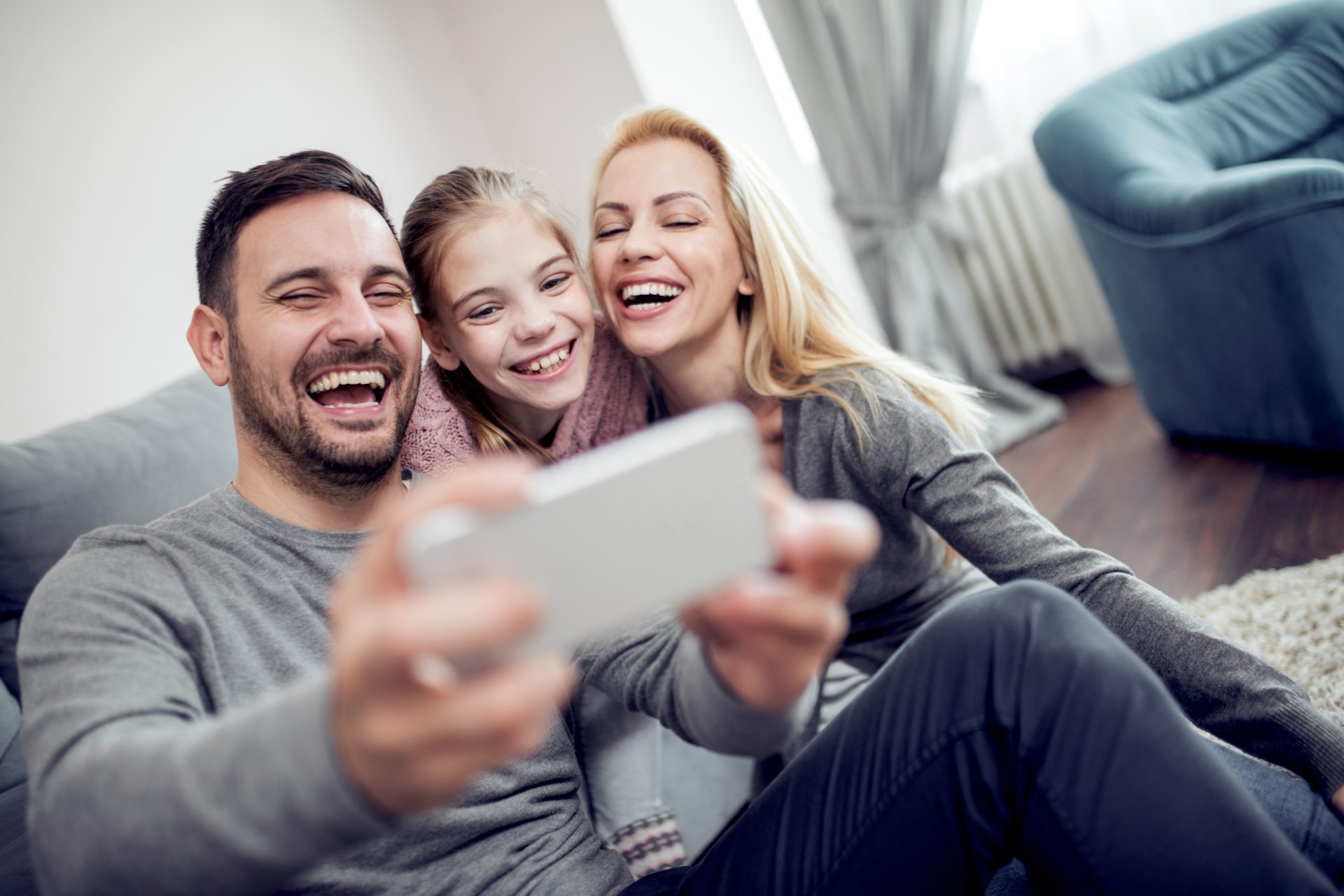 Happy family taking selfie on couch at home in the living room.