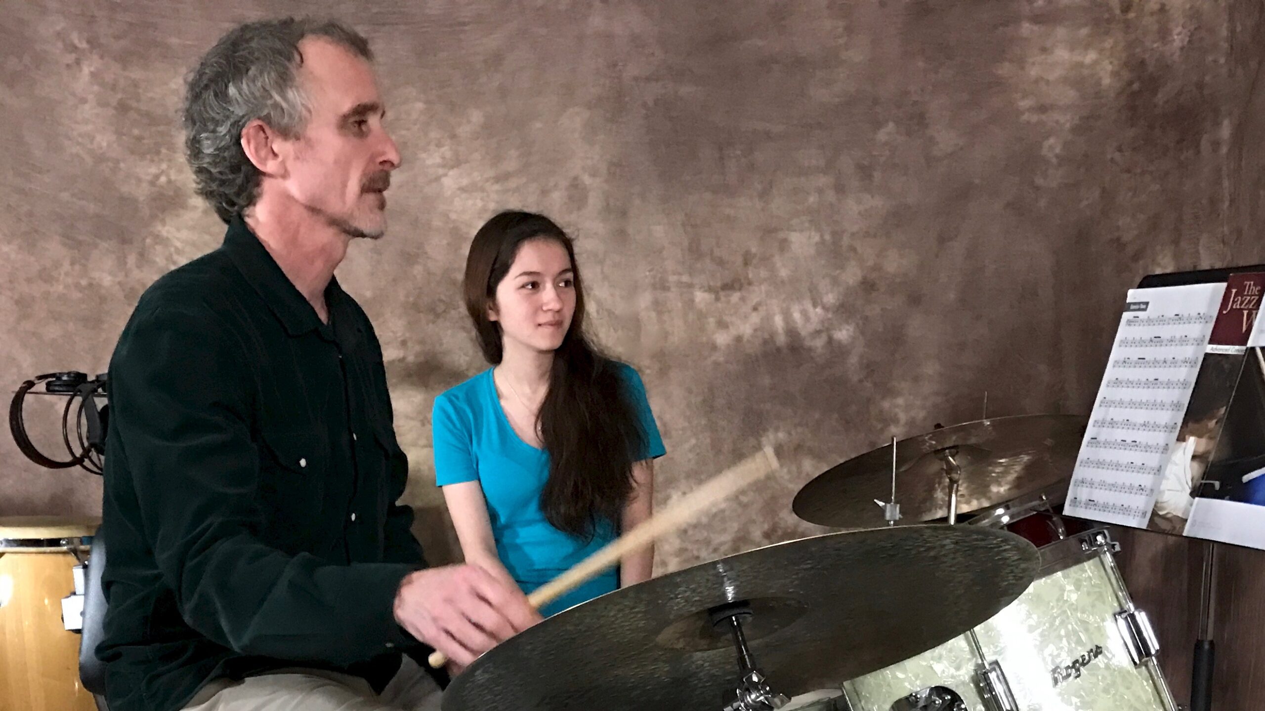 Drum teacher demonstrating for student.