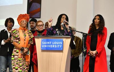 A Woman Addresses an Audience From a Podium