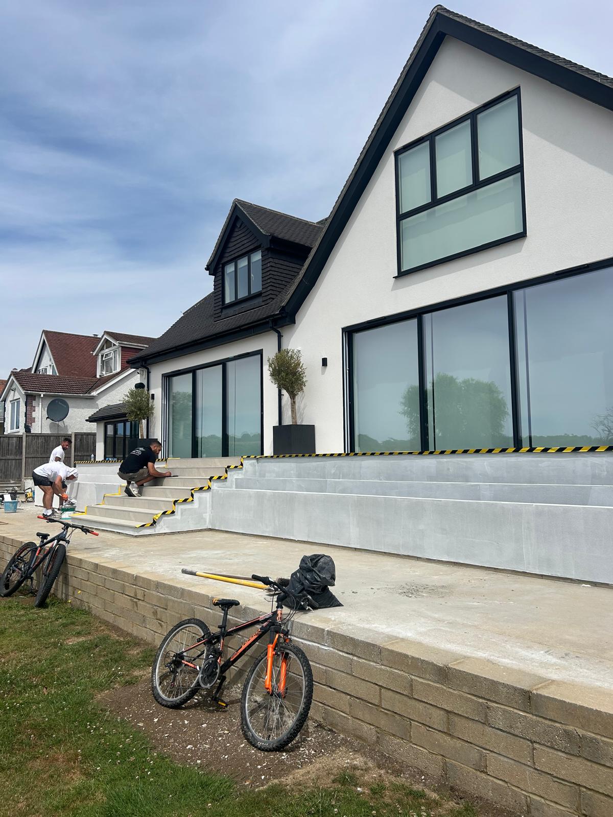 White rear elevation with dark glazing and terrace works underway