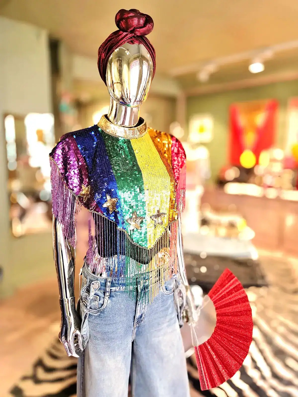 Farverig perlekappe med Pride-tema på mannequin.