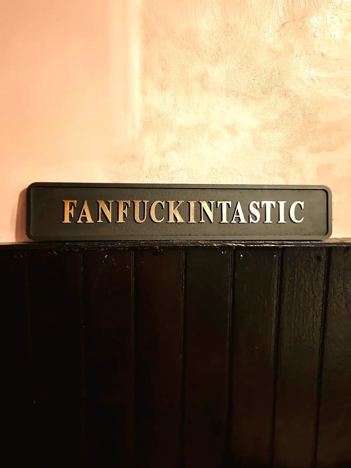Skilt med teksten 'FANFUCKINTASTIC' i sort og guld.