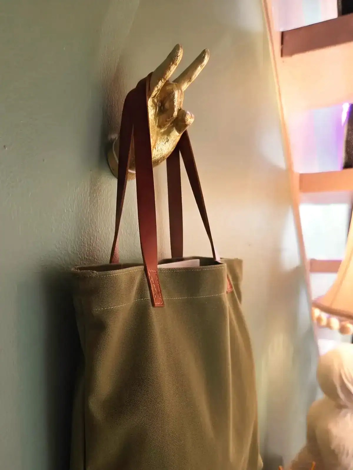 Vægkrog med håndformet hånd og taske i beige farve.