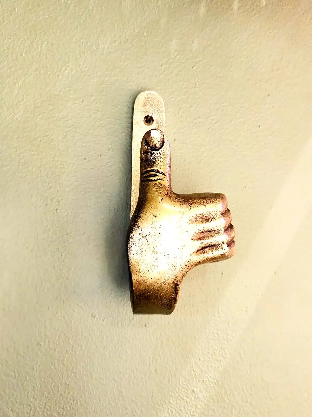Vægkrog i form af tommelfinger op i sølvfinish.