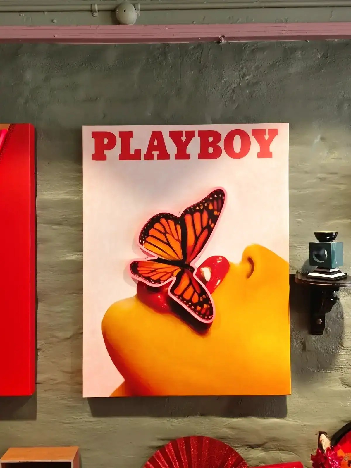 Vægspejl med Playboy-logo og sommerfugl i orange og sort farver.