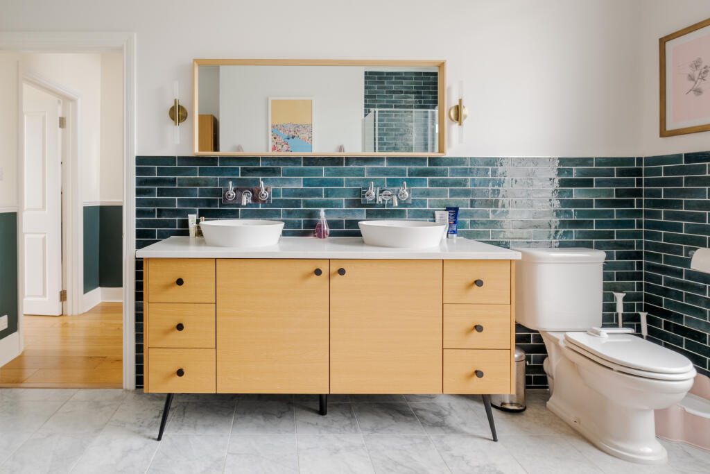 Midcentury modern bathroom featuring a floating vanity, bold geometric tile, and a round mirror