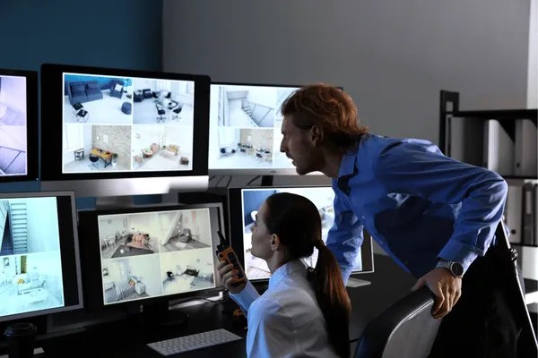 Two people using business security systems to locate each area of the building.
