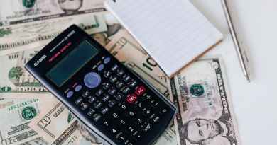 calculator and notepad placed on usa dollars stack