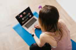 woman sitting on mat and surfing internet on laptop