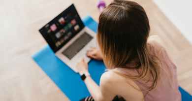 woman sitting on mat and surfing internet on laptop