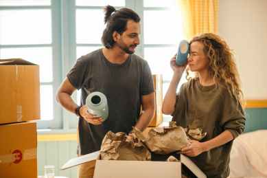 Learn how to become Mystery Shopper, friendly diverse couple unpacking fragile things after relocation