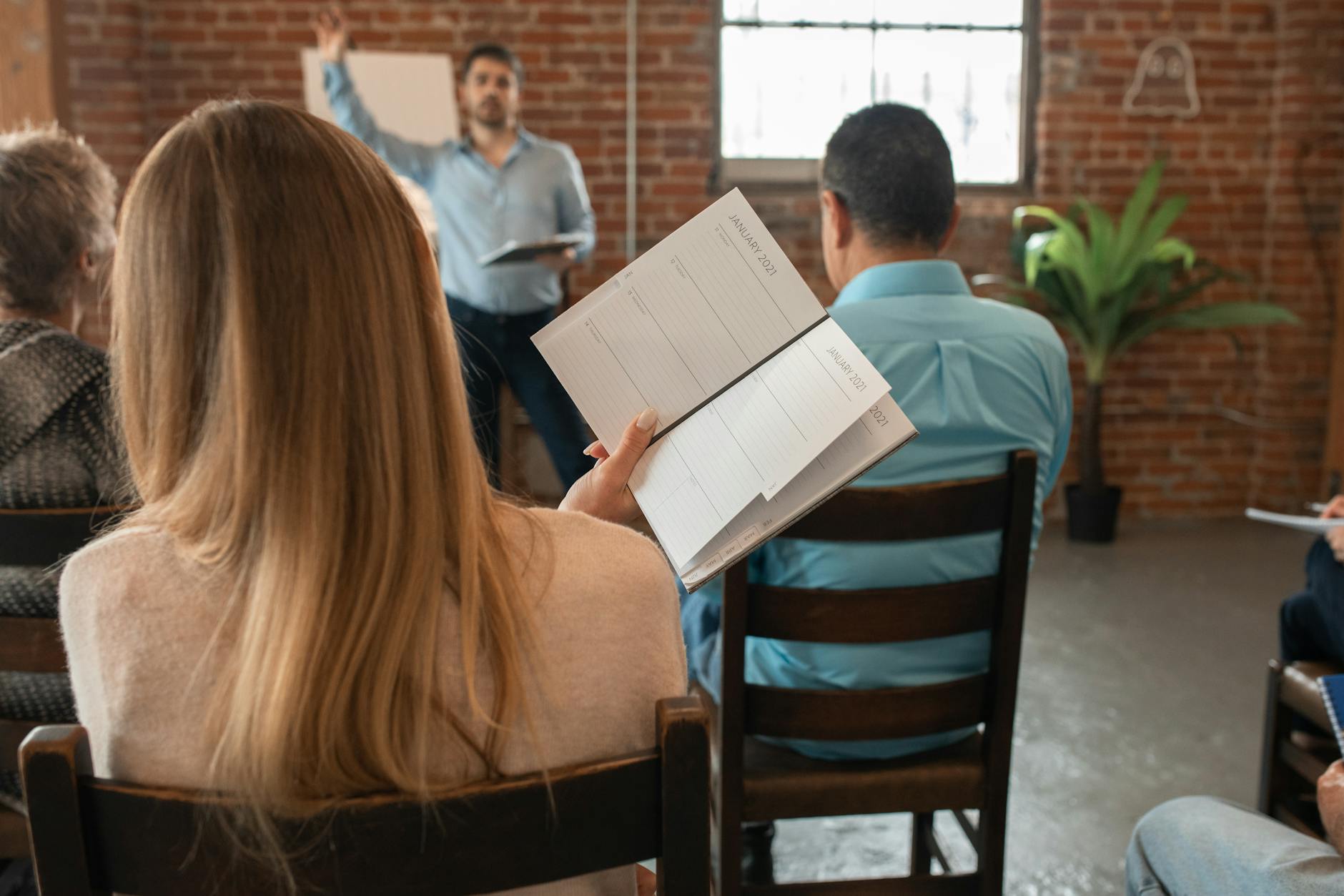 back view of blonde woman in a class holding a notebook