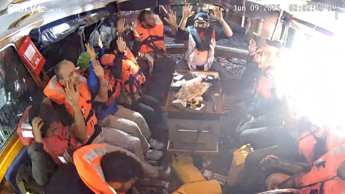 Deck scenes from the flotilla boarding sequence Passengers in life vests stand on deck as boarding teams approach during the flotilla interception.