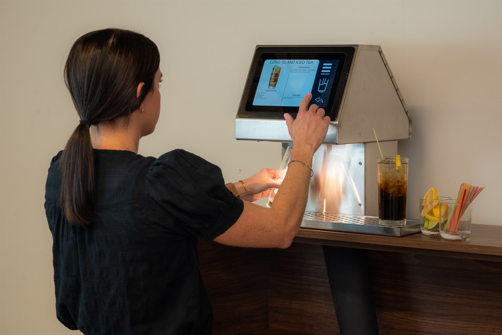 Bartender using an Easybar Easymix Cocktail Station touchscreen to dispense a Long Island Iced Tea into a glass