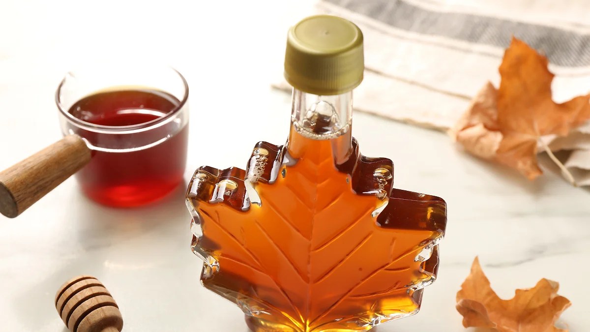 Canadian maple syrup. Amber syrup inside of a glass bottle in the shape of a maple leaf.