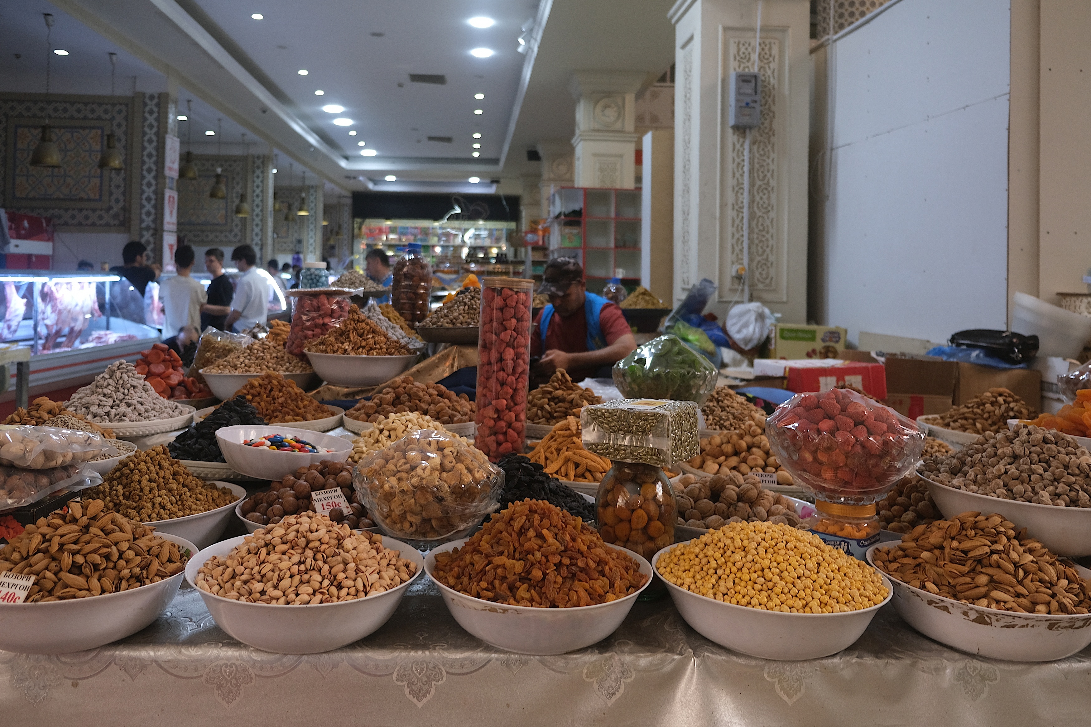 Bowls of dried fruit, pistachios, walnuts, and nuts fill a market stall at Mehrgon Bazaar in Dushanbe, Tajikistan