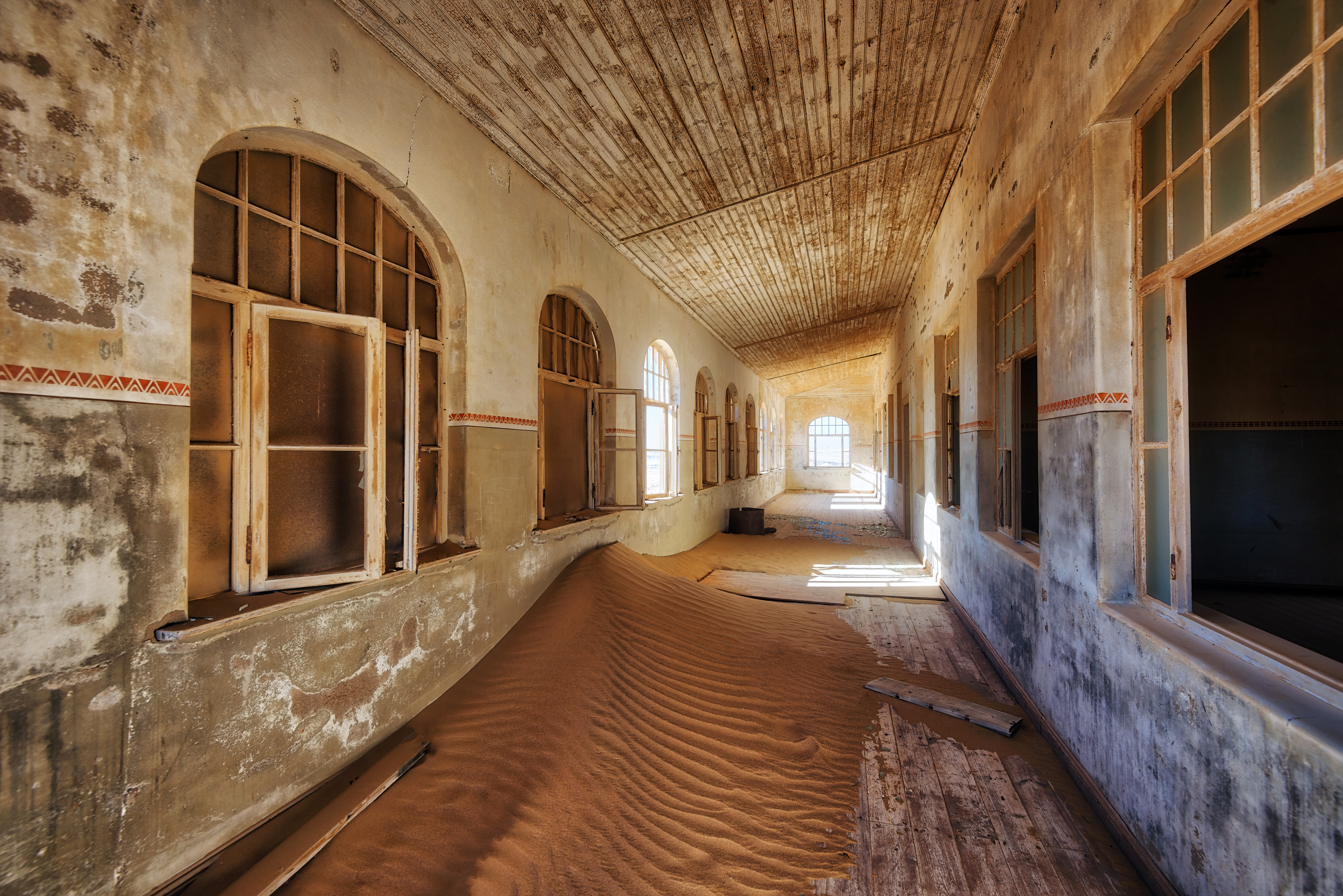 Sand drifted waist-deep through a curved corridor of arched windows inside an abandoned building at Kolmanskop, Namibia