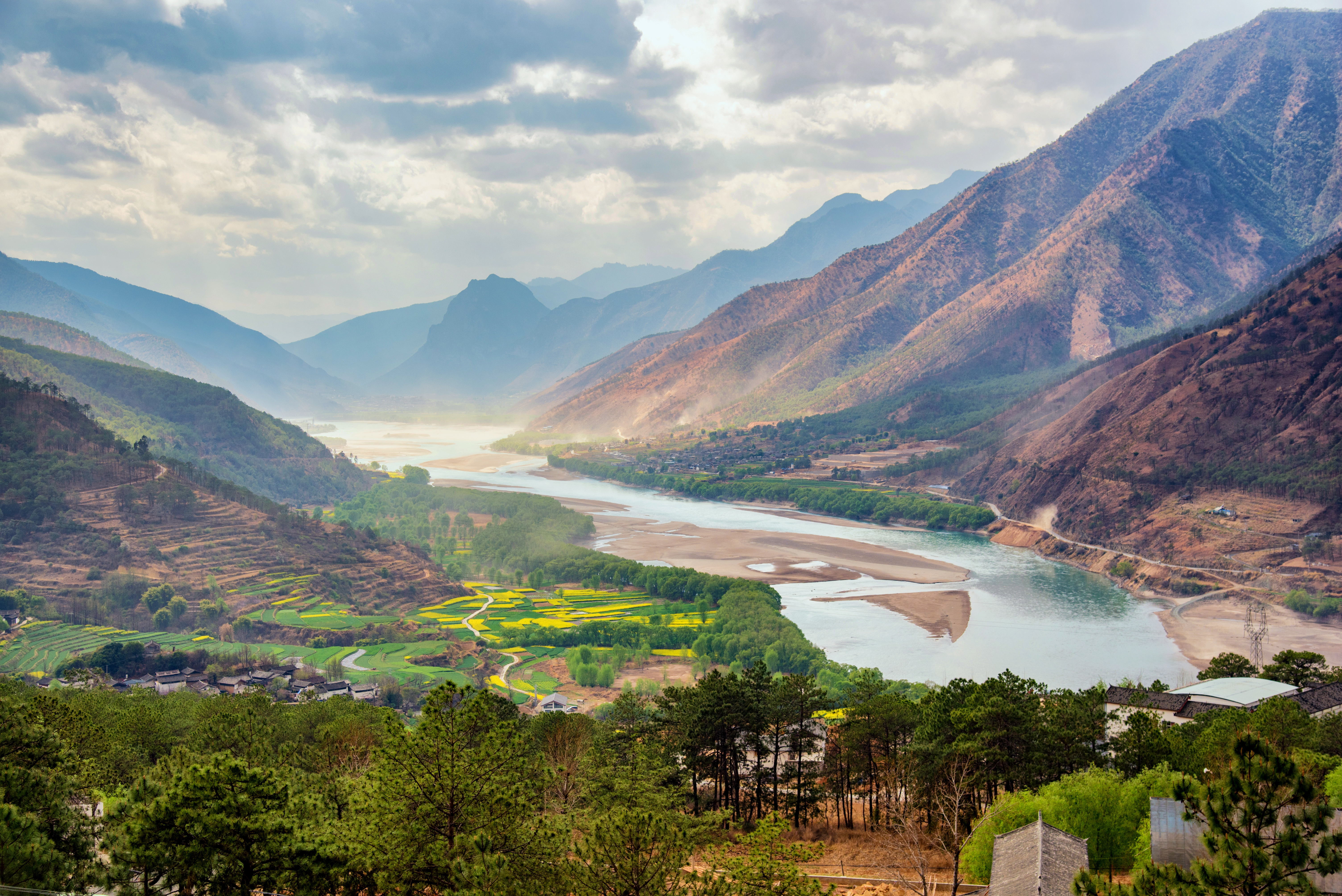 Aerial view of the Yangtze River's first great bend curving through a steep Yunnan gorge, with terraced fields and a village below