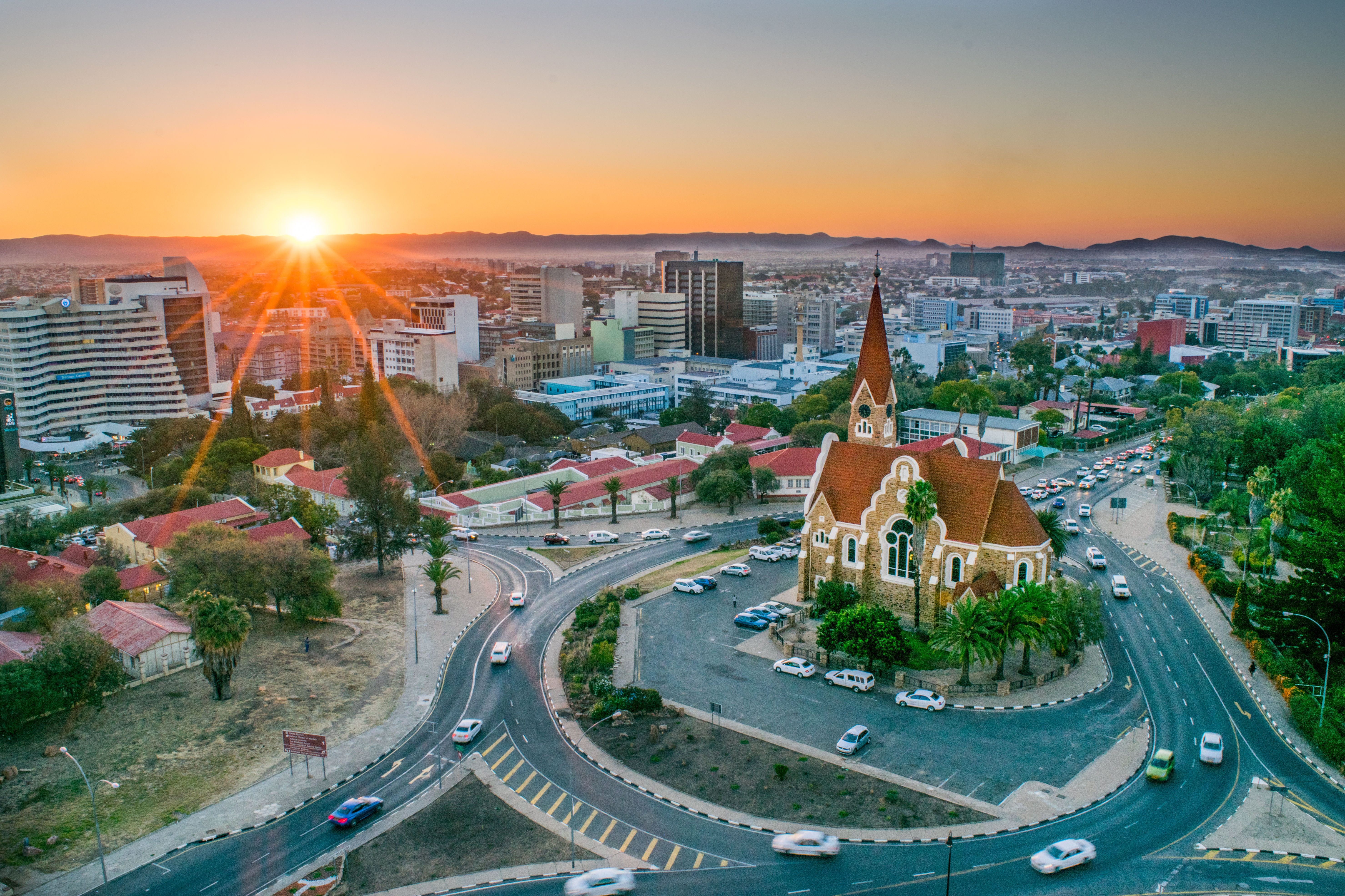 Aerial view of Windhoek at sunrise, showing the Christuskirche and a roundabout at the center of the city