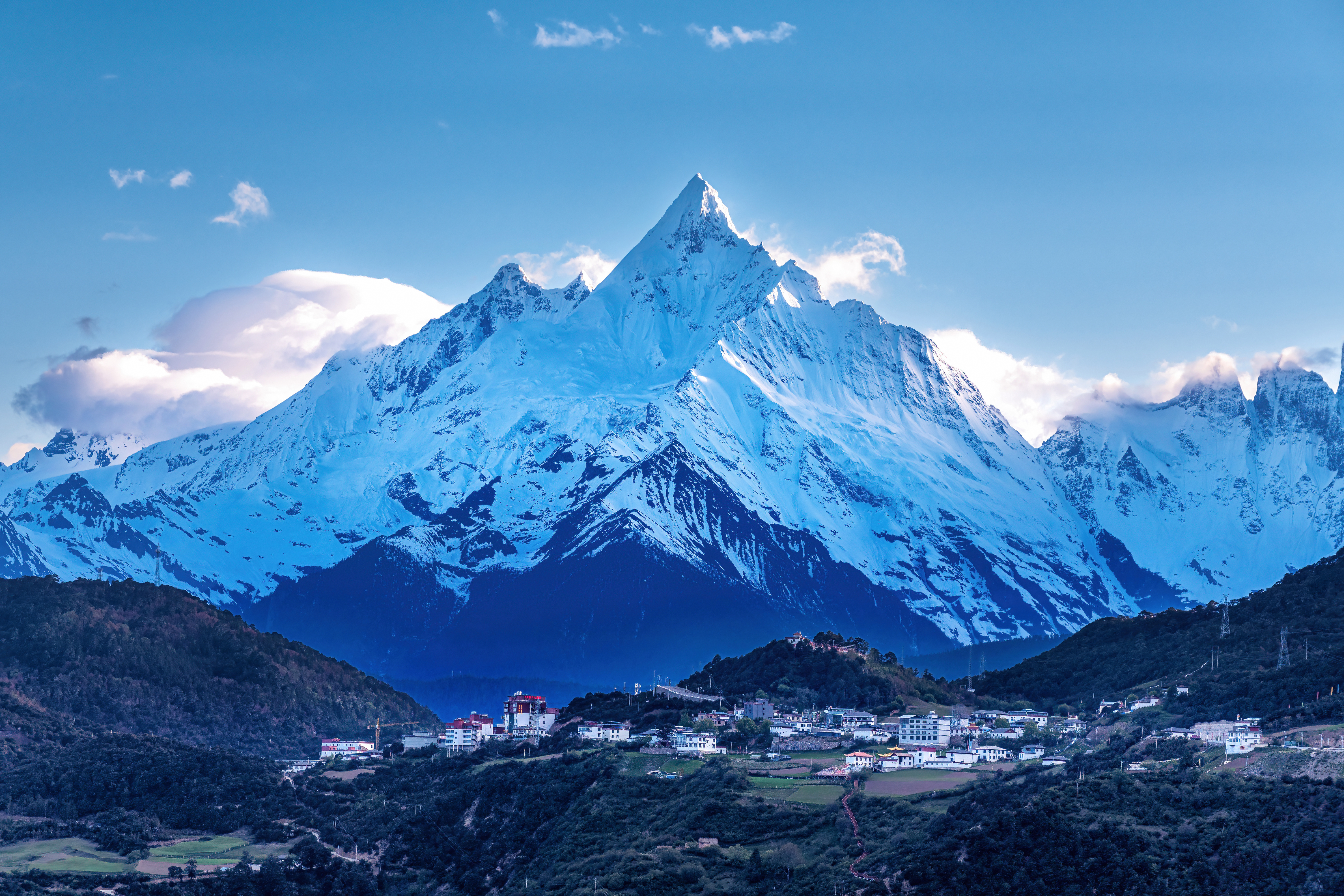 Snow-capped peak of Kawakarpo rising above a hillside village with white buildings and terraced fields, Yunnan, China