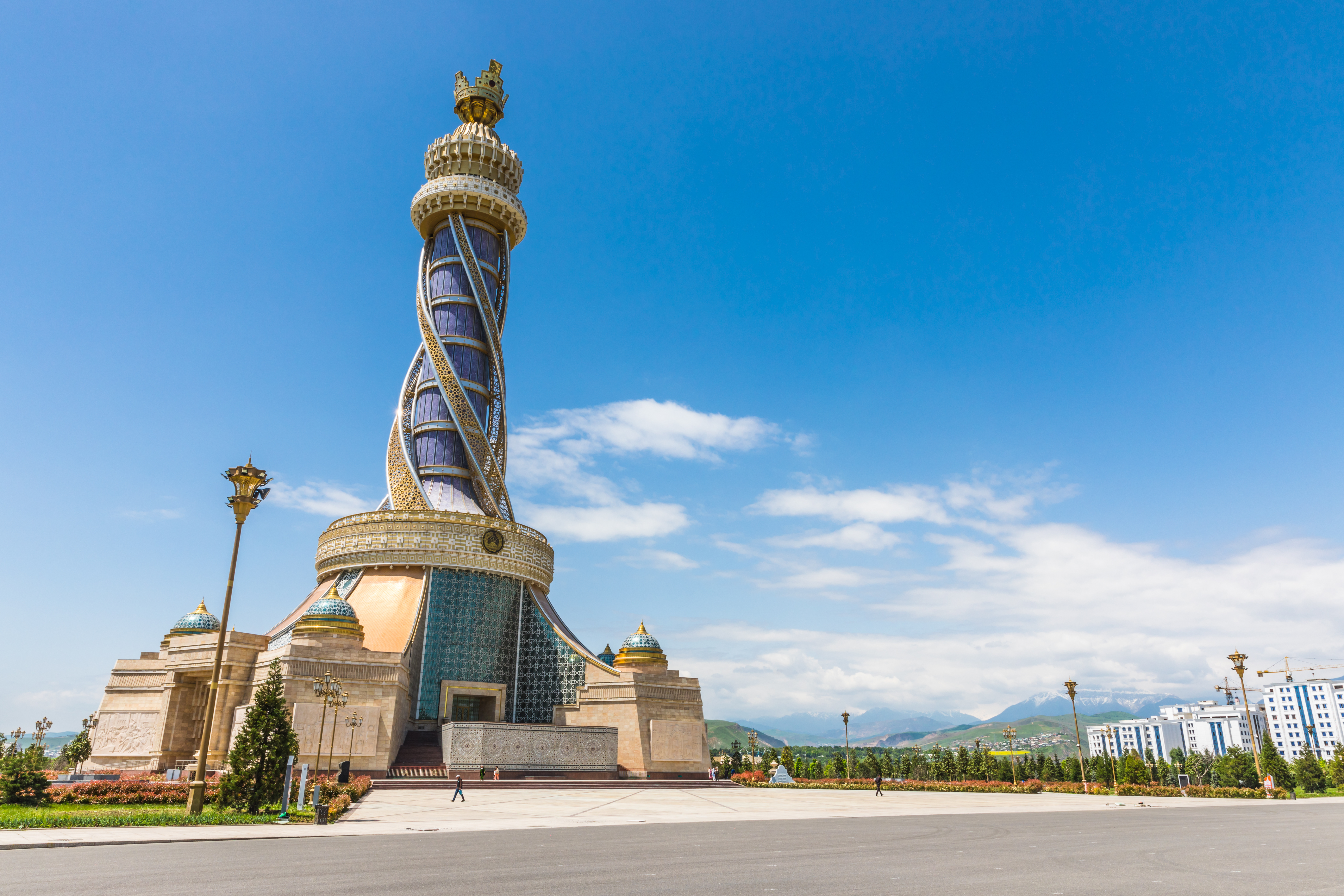 Twisting spiral tower topped with a crown-shaped structure at the Istiklol complex in Dushanbe, Tajikistan, against a clear blue sky
