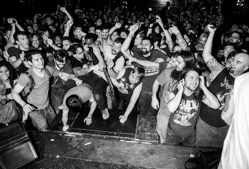 A crowd at a concert near the front of the stage moshing.