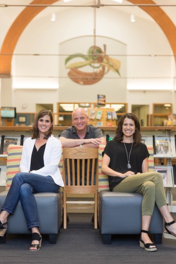 two women and a man at the library