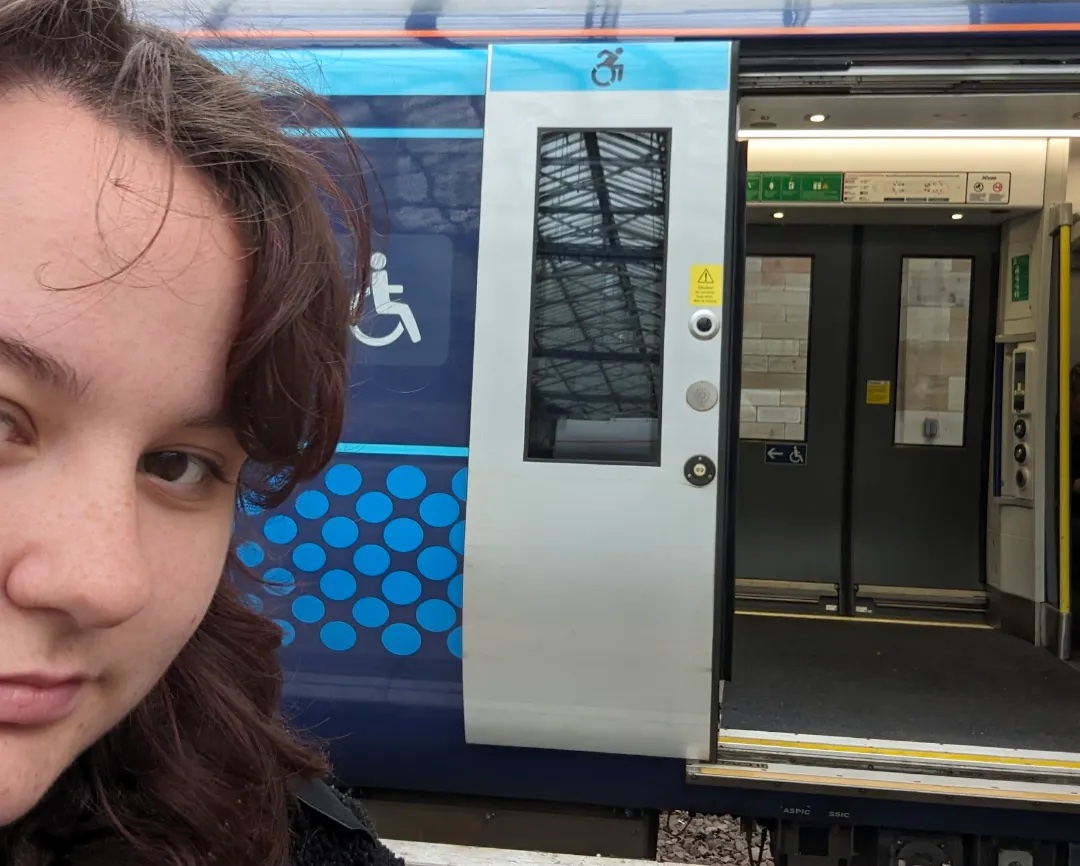 Selfie of Kayleigh O'Neill in front of the open doors of a ScotRail train.