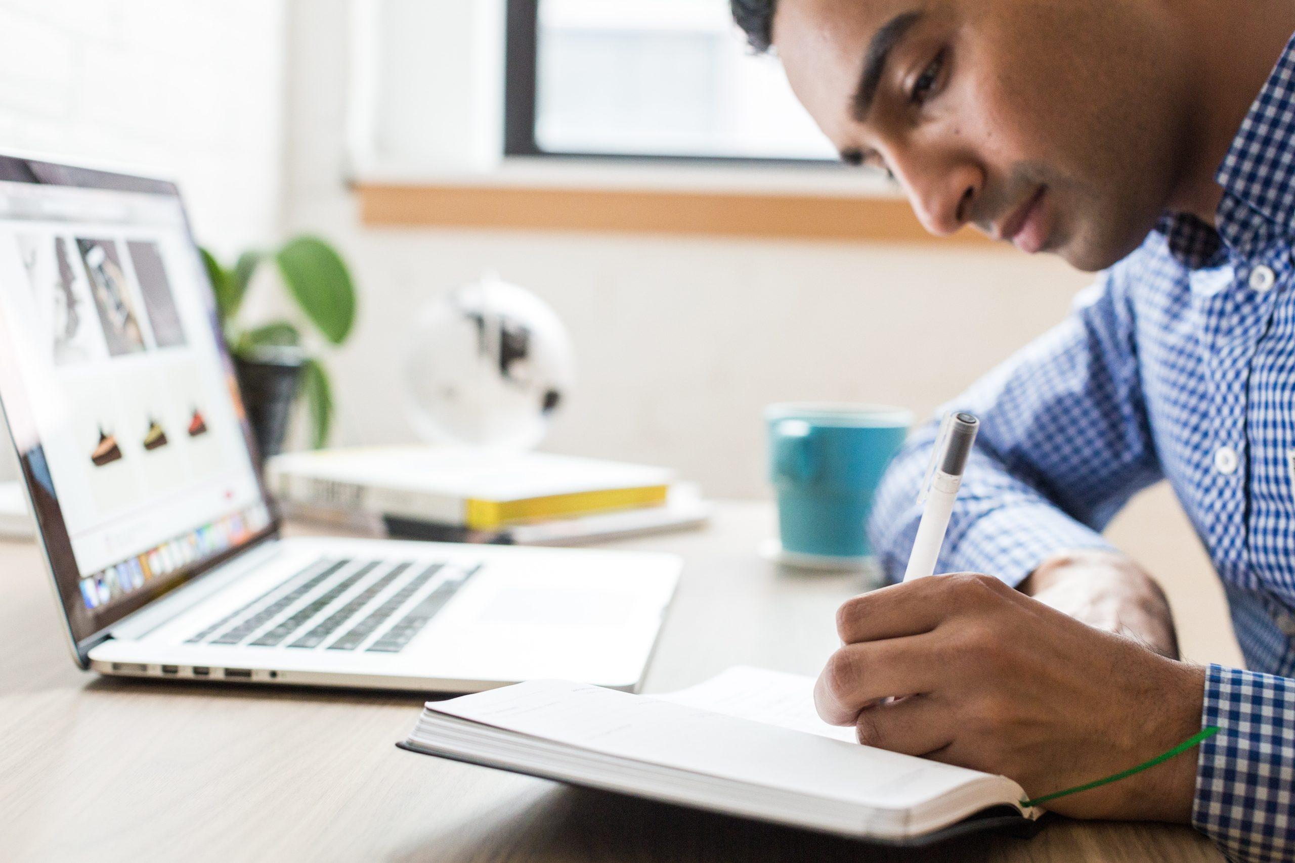 person writing notes during online learning course